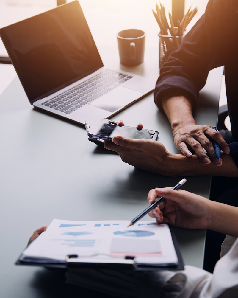 Imagebild Tagung: Hände welche ein Smartphone und Statistiken in der Hand halten und besprechen